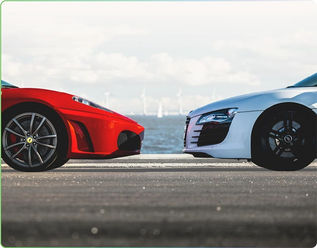 a red sports car and a white sports car nose to nose on a seafront road