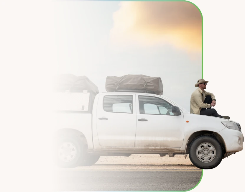 a man sitting on the bonnet of a loaded bakkie at sunset